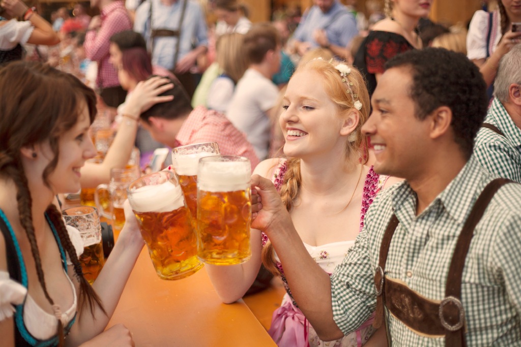 Friends Toasting with Beer Steins in Dirndl and Lederhosen at Oktoberfest Festival.jpg